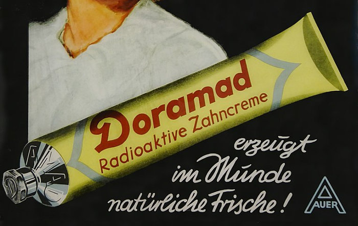 Ausschnitt aus altem Werbeposter: gelbe Tube mit kleinem Verschluss und der Aufschrift »Doramad – Radioaktive Zahncreme«, dazu der Slogan: »erzeugt im Munde natürliche Frische!«