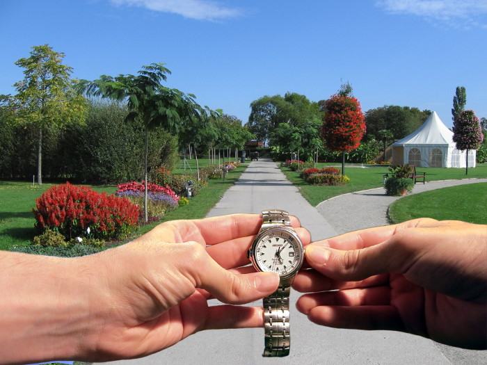 Hände verdrehen Armbanduhr vor sommerlicher Kulisse.