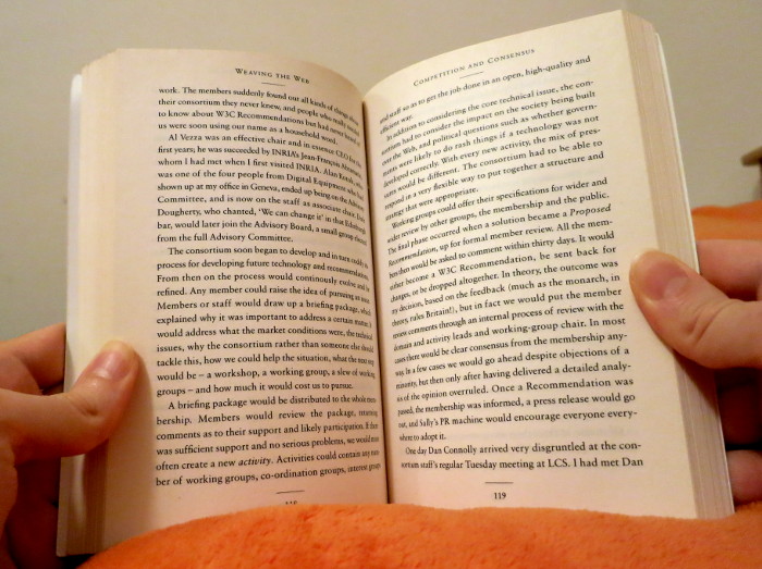 Aufgeschlagenes Buch mit dichtem Blocksatz, gehalten in zwei Händen.